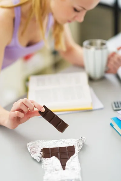 Närbild på tonåring flicka äta choklad medan du studerar i kök — Stockfoto