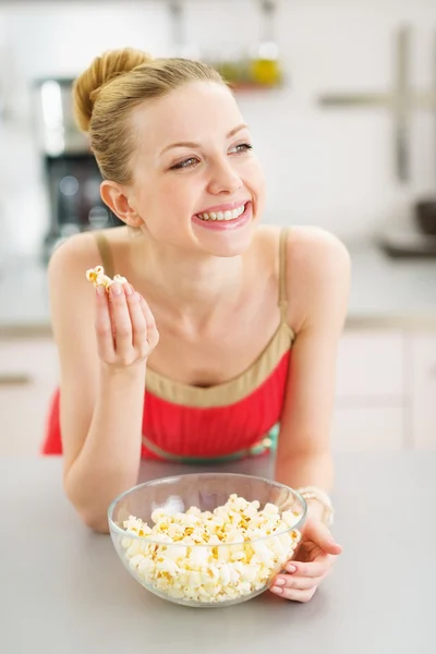 Счастливая девочка-подросток ест попкорн на кухне — стоковое фото