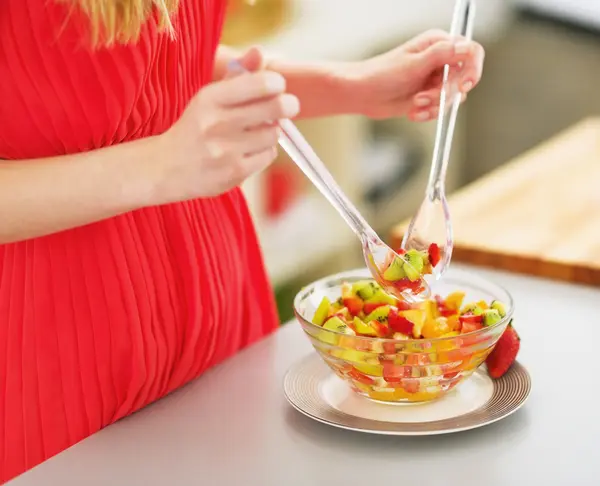 Closeup on young woman mixing fresh fruits salad — Stock Photo, Image