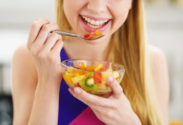 Gros plan sur une jeune femme mangeant de la salade de fruits frais dans la cuisine — Photo