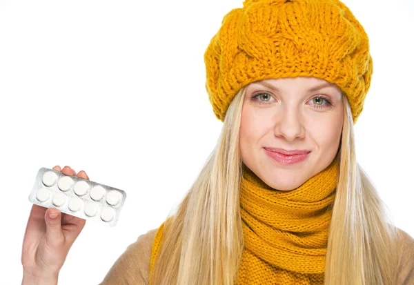 Feliz joven mujer en sombrero y bufanda mostrando paquete de pastillas — Foto de Stock