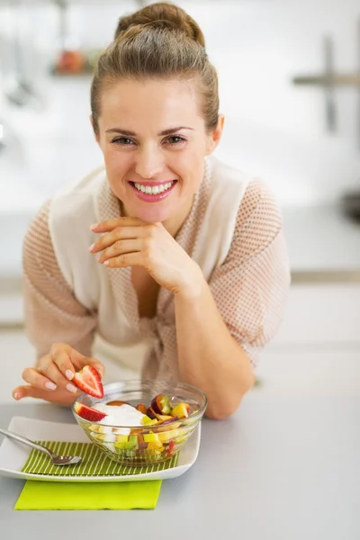 Glückliche junge Hausfrau schmückt Obstsalat — Stockfoto