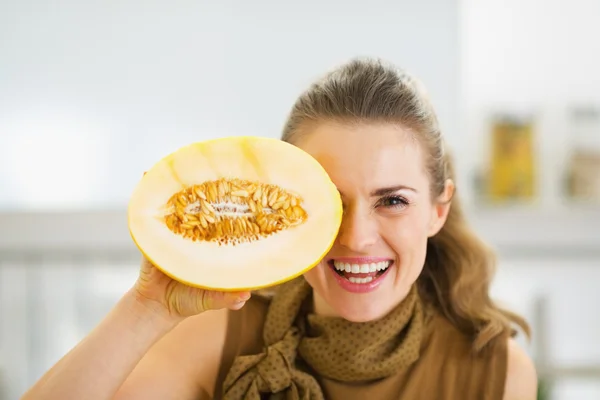 Sonriente joven ama de casa sosteniendo rebanada de melón delante de los ojos —  Fotos de Stock