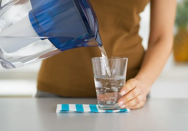 Primer plano en ama de casa vertiendo agua en el vidrio del filtro de agua Imágenes De Stock Sin Royalties Gratis