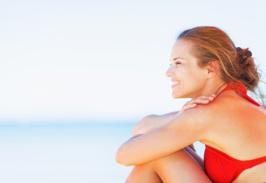 kumsalda oturuyor ve kopya alanı üzerinde seyir mutlu bir genç kadın