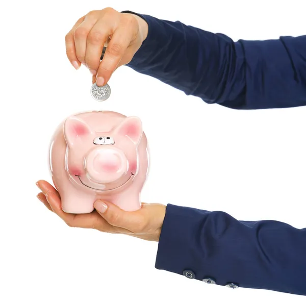 Closeup on business woman hands putting coin into piggy bank — Stock Photo, Image