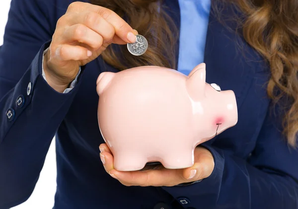 Primer plano de la mujer de negocios poniendo moneda en alcancía —  Fotos de Stock