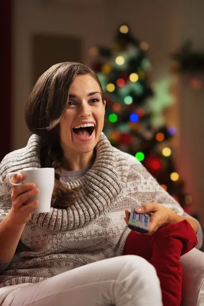 Sorprendido joven mujer con taza de chocolate caliente viendo la televisión —  Fotos de Stock