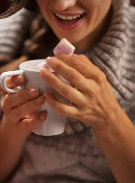 Close-up op jonge vrouw marshmallow eten van kopje warme chocol — Stockfoto