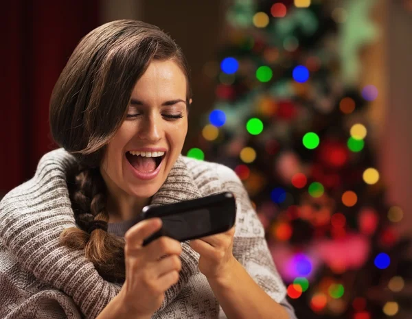 Verrast jonge vrouw leest sms in de buurt van de kerstboom — Stockfoto