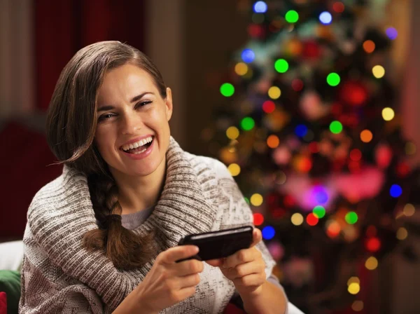 Feliz joven escribiendo sms cerca del árbol de Navidad —  Fotos de Stock