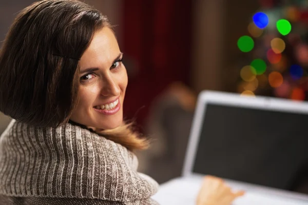 Gelukkig jonge vrouw met laptop voor kerstboom — Stockfoto