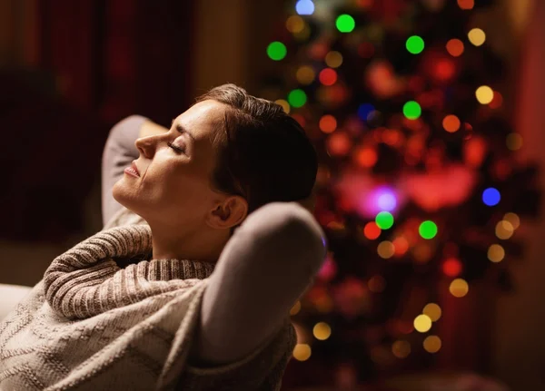 Rilassato giovane donna seduta in poltrona di fronte a Natale tr — Foto Stock