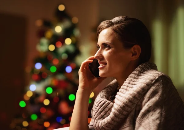 Happy young woman talking cell phone in front of christmas tree — Stock Photo, Image