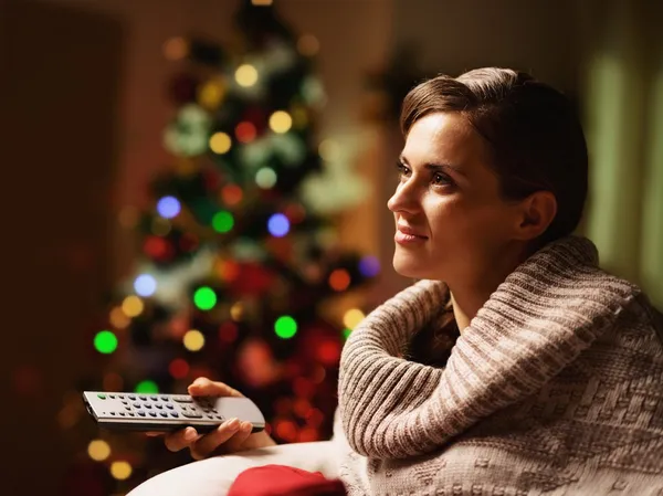 Feliz joven mujer viendo la televisión frente al árbol de Navidad —  Fotos de Stock