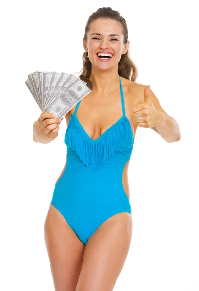 Smiling young woman in swimsuit showing fan of dollars and thumb — Stock Photo, Image