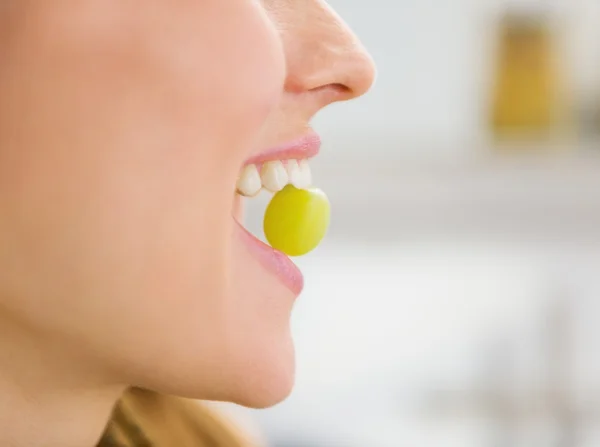 Closeup on young woman holding grape in mouth — Stock Photo, Image