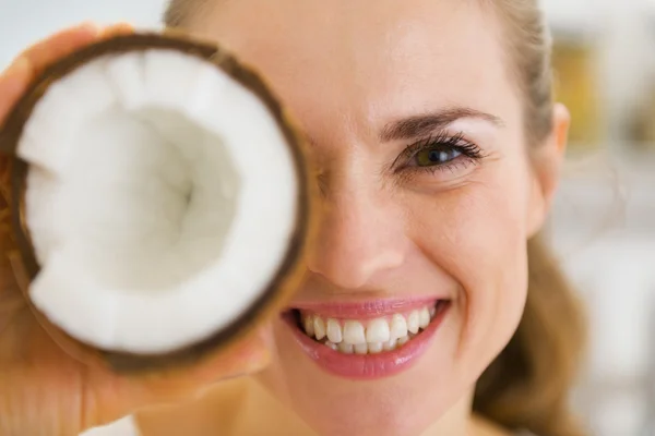 Happy young woman holding coconut piece in front of eye — Stock Photo, Image