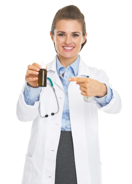 Улыбающаяся женщина-врач указывает на бутылку с лекарством — стоковое фото
