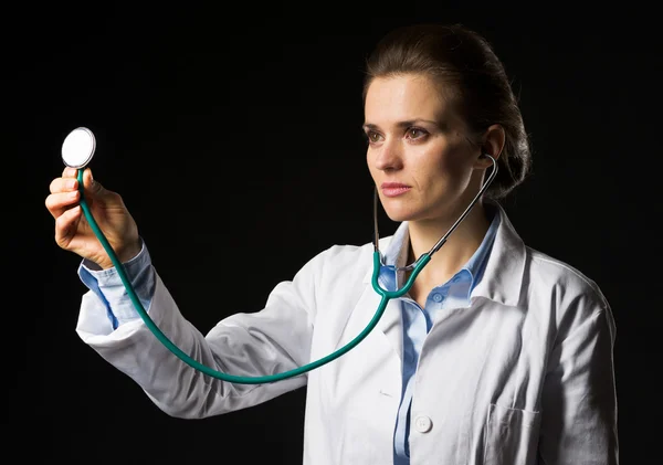 Mulher médica usando estetoscópio isolado em preto — Fotografia de Stock