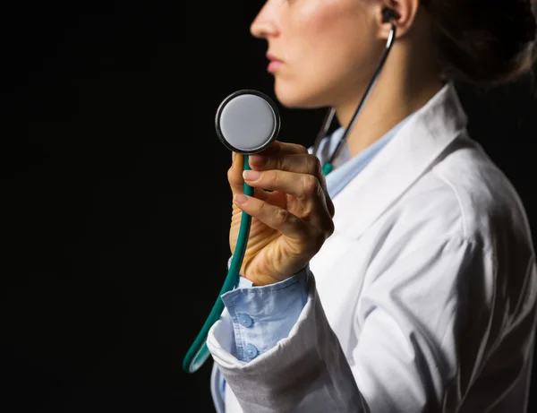 Крупним планом на лікаря жінка використовує стетоскоп ізольовані на чорному — стокове фото