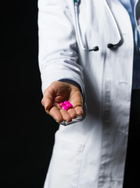 Primer plano de las píldoras en la mano de la mujer médico aislado en negro —  Fotos de Stock