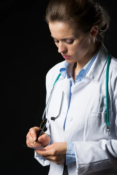 Doctor woman writing prescription isolated on black — Stock Photo, Image