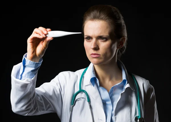 Mujer doctora mirando el termómetro aislado en negro —  Fotos de Stock