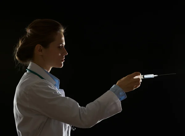 Silueta de la mujer doctora usando jeringa aislada en negro — Foto de Stock