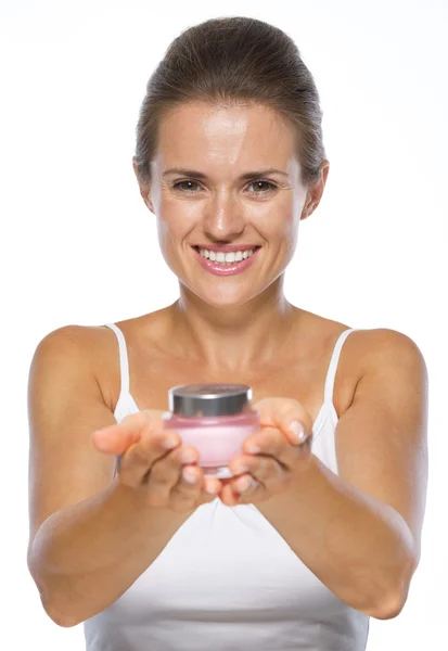 Smiling young woman giving cream bottle — Stock Photo, Image