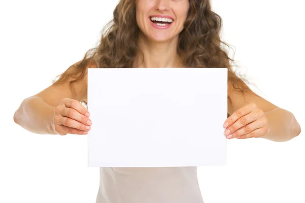 Primer plano de la joven sonriente mostrando papel en blanco — Foto de Stock