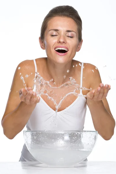 Glückliche junge Frau, die beim Waschen des Gesichts Wasser spritzt — Stockfoto