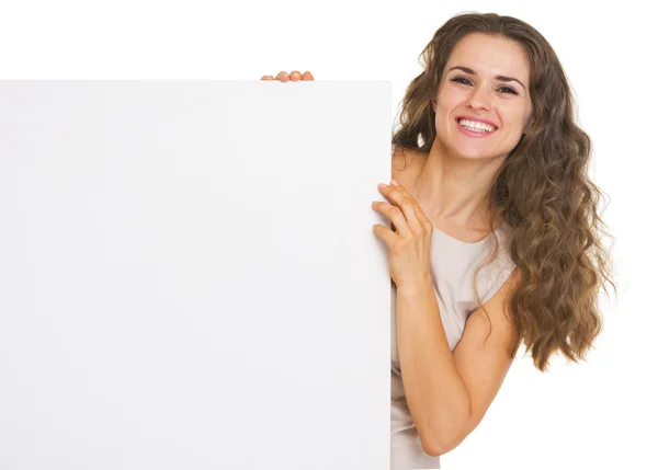 Glückliche junge Frau zeigt leere Plakatwand — Stockfoto