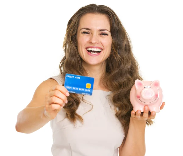 Joyeux jeune femme montrant carte de crédit et tirelire — Photo