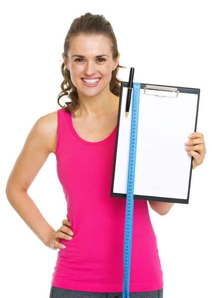 Treinador de fitness feliz mostrando prancheta em branco com fita métrica — Fotografia de Stock