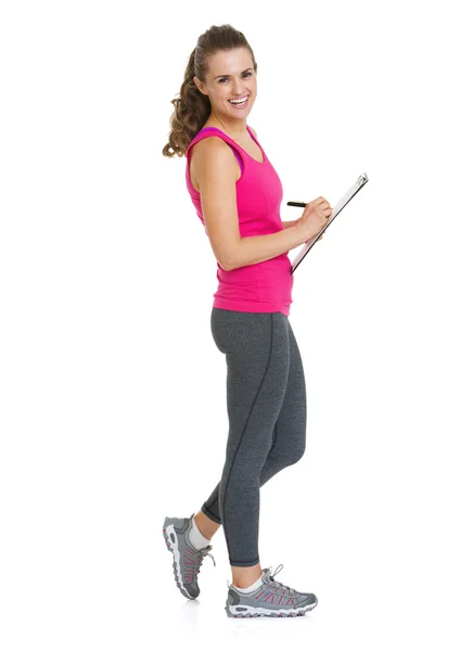 Full length portrait of smiling fitness trainer writing — Stock Photo, Image