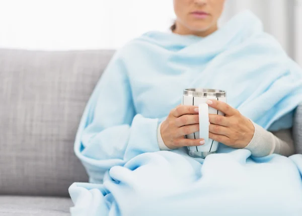 Primer plano en la taza con bebida caliente en la mano de la mujer enferma — Foto de Stock