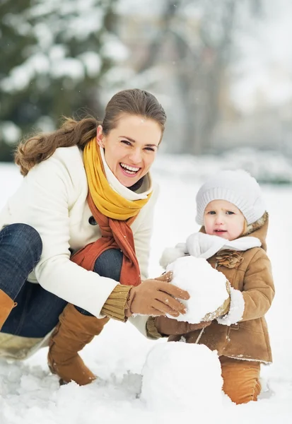 Glückliche Mutter und Baby beim Schneemannbasteln im Winterpark — Stockfoto