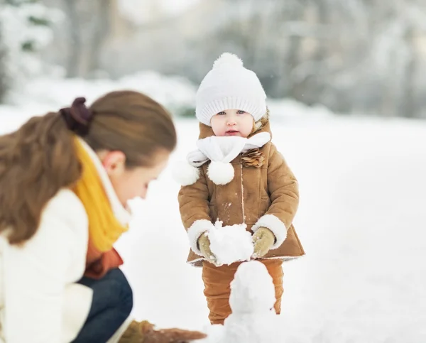 Felice madre e bambino facendo pupazzo di neve nel parco invernale — Foto Stock