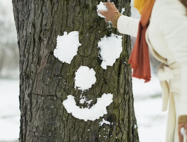 Jonge vrouw gezicht voor boom met behulp van sneeuw maken — Stockfoto