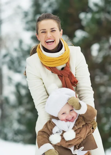 Feliz madre jugando con el bebé en el parque de invierno — Foto de Stock