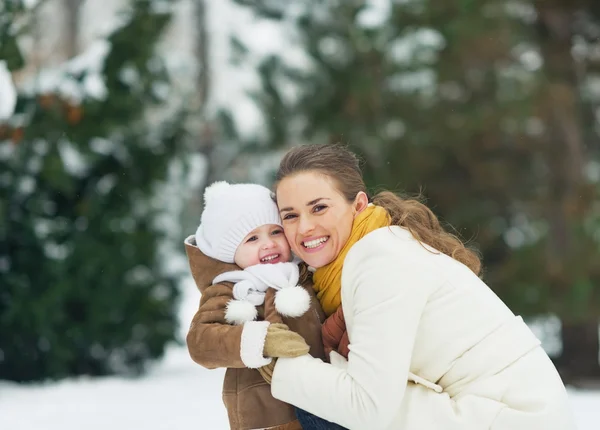 Portrait of happy mother and baby in winter park — Stock Photo, Image