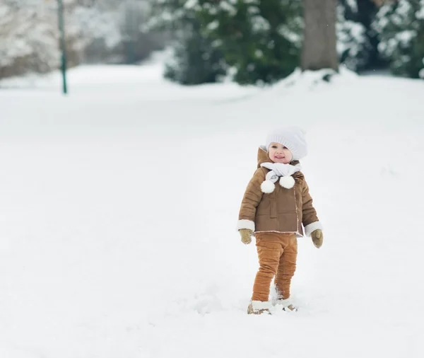 Glimlachende baby wandelen in winter park — Stockfoto