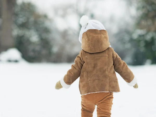 Bebé caminando en el parque de invierno. visión trasera — Foto de Stock