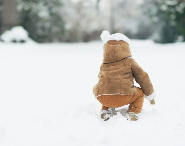 Baby playing with snow in winter park . rear view — Stock Photo, Image