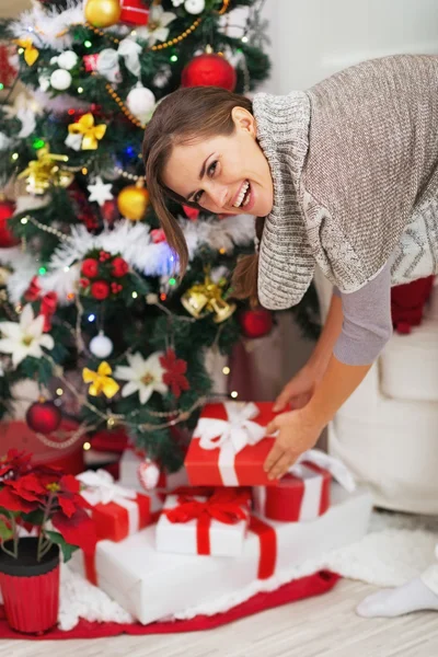 Glückliche junge Frau nimmt Weihnachtsgeschenkschachtel unter dem Christkind — Stockfoto