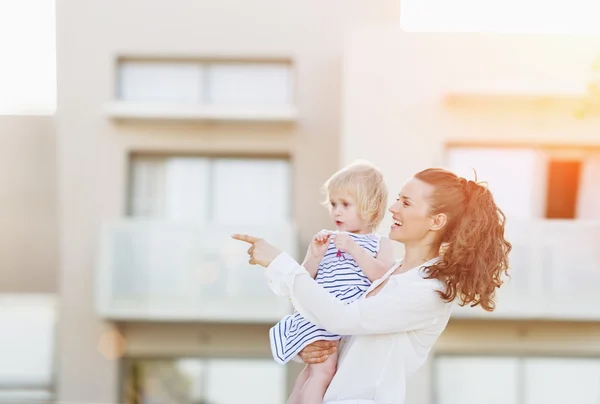 Glad mamma med baby står framför hus byggnad och p — Stockfoto