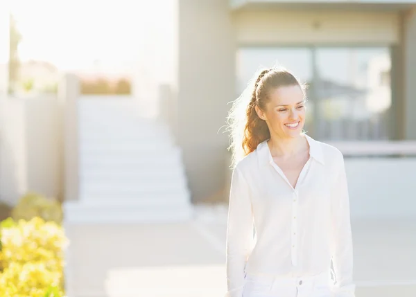 Portrait of smiling young woman standing in front of house build — Stock Photo, Image