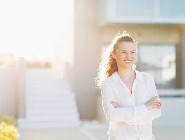 Portrait of happy young woman standing in front of house buildin — Stock Photo, Image