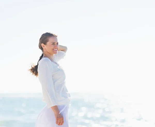 Porträt einer lächelnden jungen Frau am Ufer des Meeres, die in Seenot blickt — Stockfoto